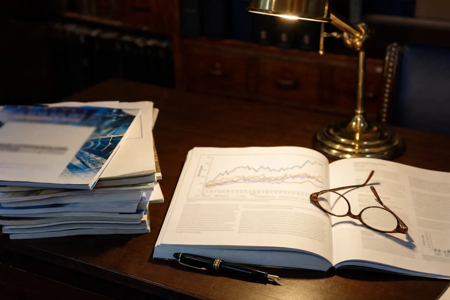 Organized study desk with an open medical journal, reading glasses, and warm lamp light